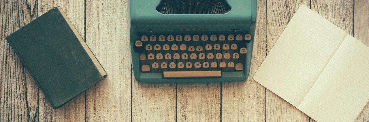 book, typewriter, and open journal on a wooden background